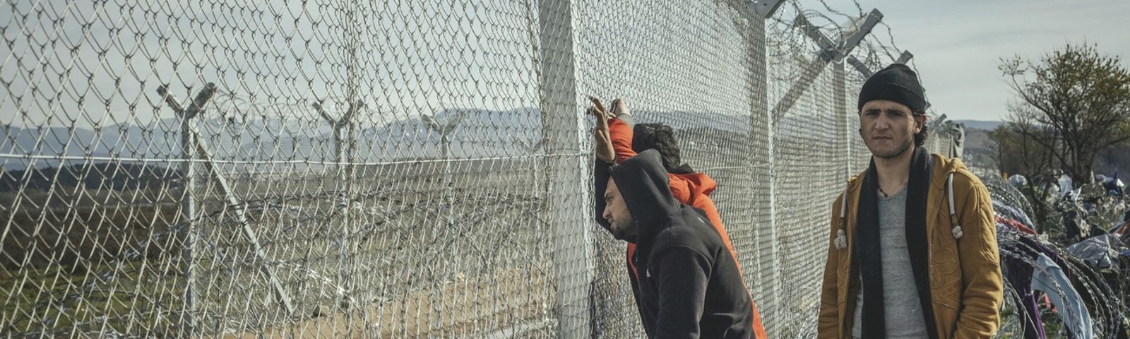 FlĂĽchtlinge stehen an einem Zaun