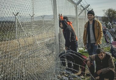 FlĂĽchtlinge stehen an einem Zaun